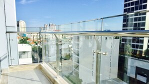Un balcon moderne en verre offrant une vue dégagée sur le paysage urbain.