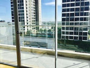 Een hoog gebouw met meerdere verdiepingen, grote ramen en uitzicht op andere gebouwen en groen.