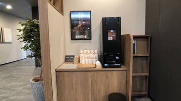 Un espace café en libre-service équipé d’une machine à café, de tasses et d’un panneau explicatif.