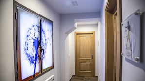 Um corredor com uma porta de madeira, um radiador e um quadro emoldurado na parede.