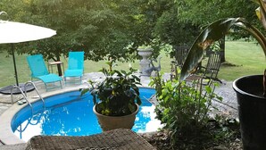 A backyard with a swimming pool, blue chairs, a wicker bench, and a bird statue. - Le Peyrail (Les Lèves-et-Thoumeyragues)