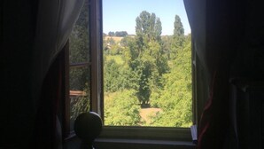 A room with a window overlooking a green landscape. - Le Peyrail (Les Lèves-et-Thoumeyragues)
