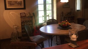 A dining area with a round table, chairs, a guitar, and a window with natural light. - Le Peyrail (Les Lèves-et-Thoumeyragues)
