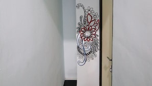 Een smalle gang met een zwart-wit geruit vloerkleed, een witte deur met bloemenmotief en nummer 206 op de muur.