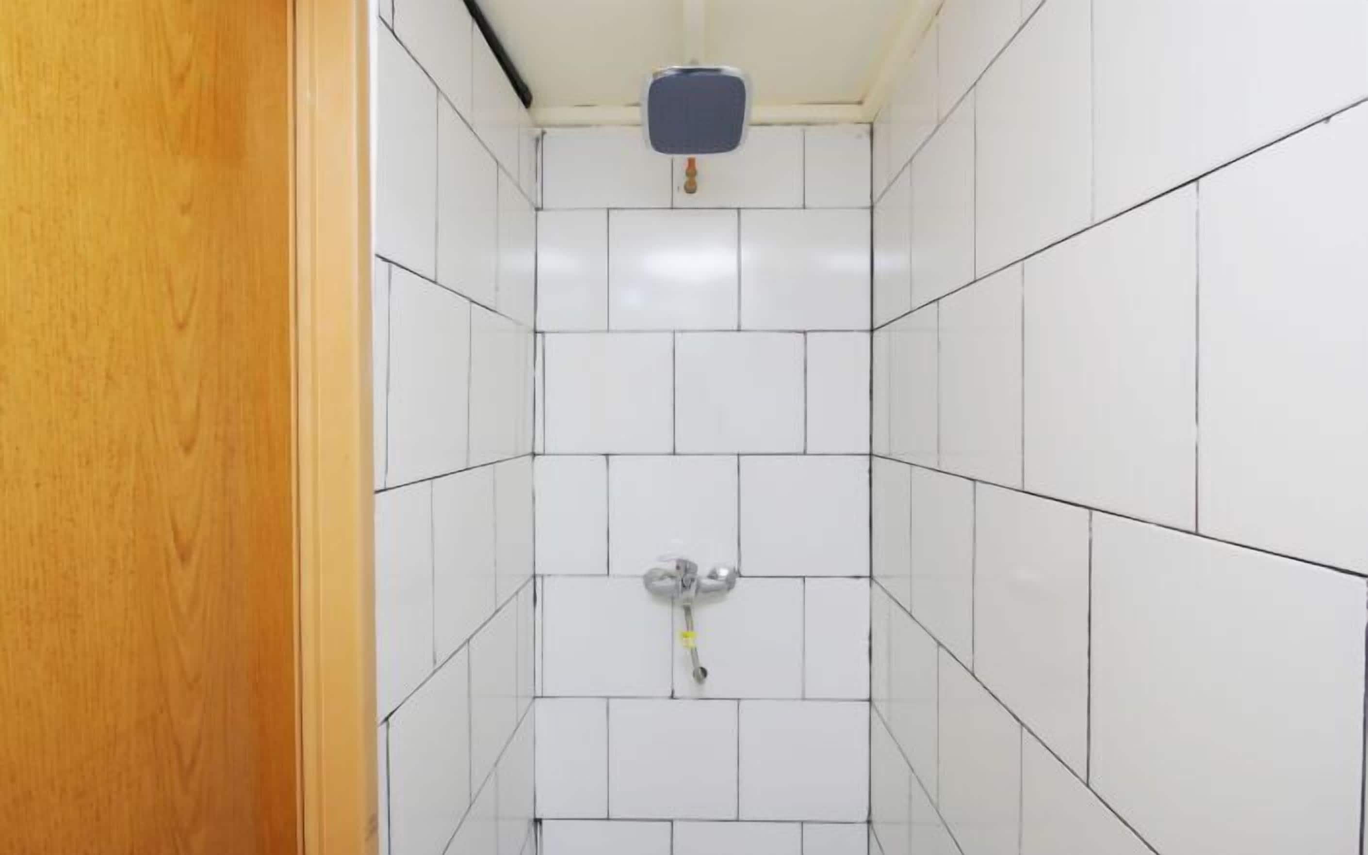 A small, tiled bathroom with a toilet and a hand dryer.