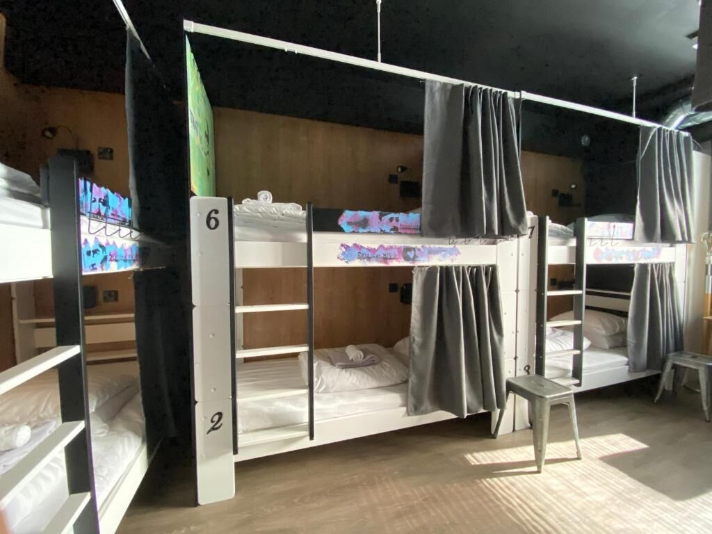 A bunk bed room with a number 6 bunk and a number 2 bunk, a small stool, and a wooden floor.