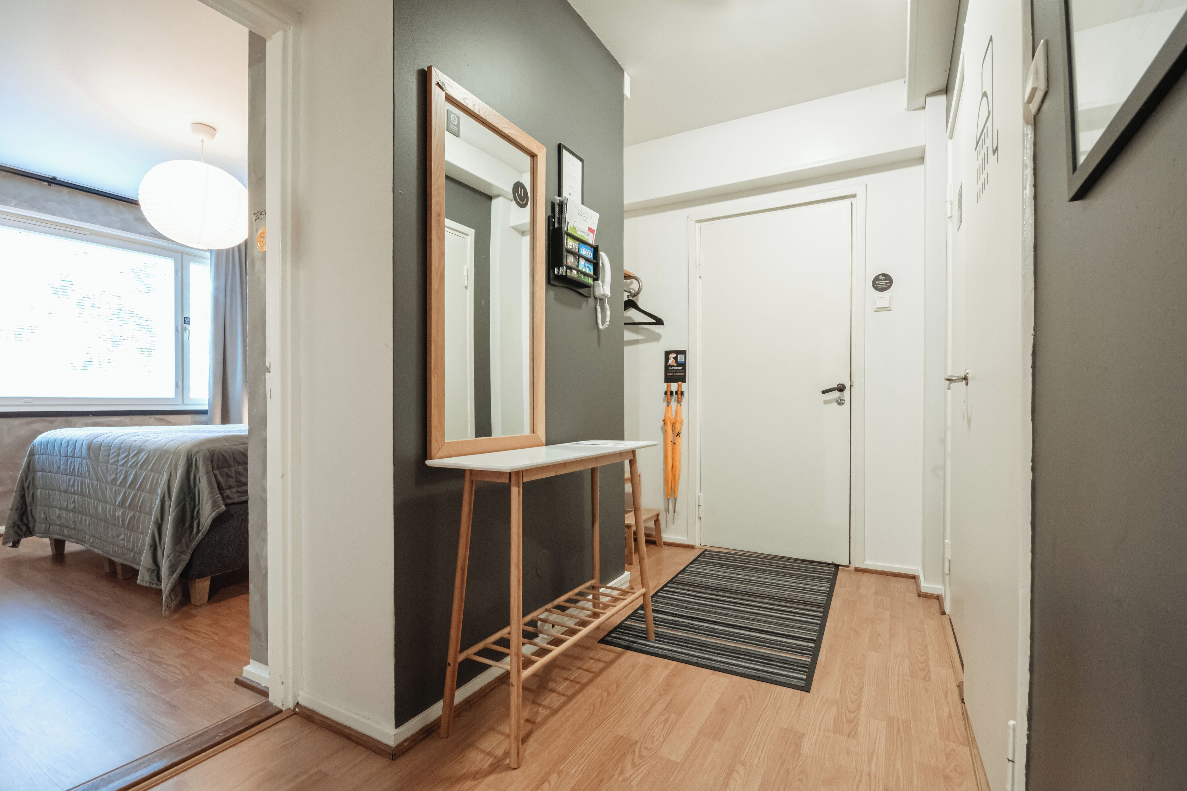 A modern hotel room with a bed, bedside table, and a large mirror.