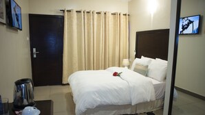 Una habitación de hotel con cama, cafetera, televisor y cortina.