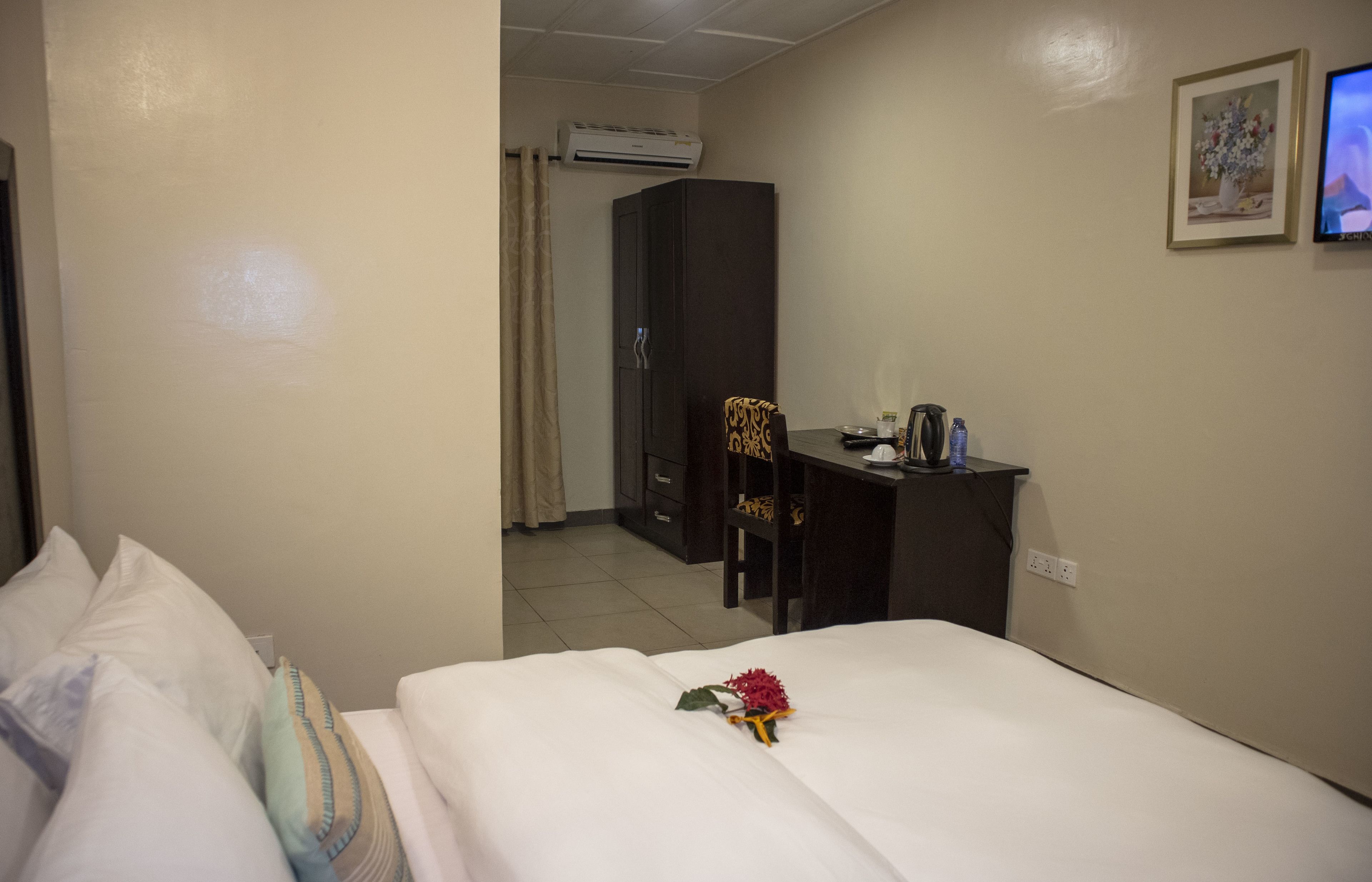A hotel room with a bed, a desk, an air conditioner, a wardrobe, and a television.