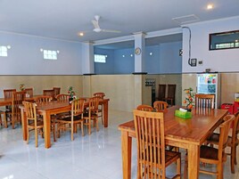 Un comedor amplio con mesas y sillas de madera, un ventilador de techo y un refrigerador lleno de bebidas.