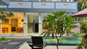 A hotel with a pool, outdoor seating, and a covered area with stairs leading to the upper floor. - Serangan Inn Mimba (Padangbai)