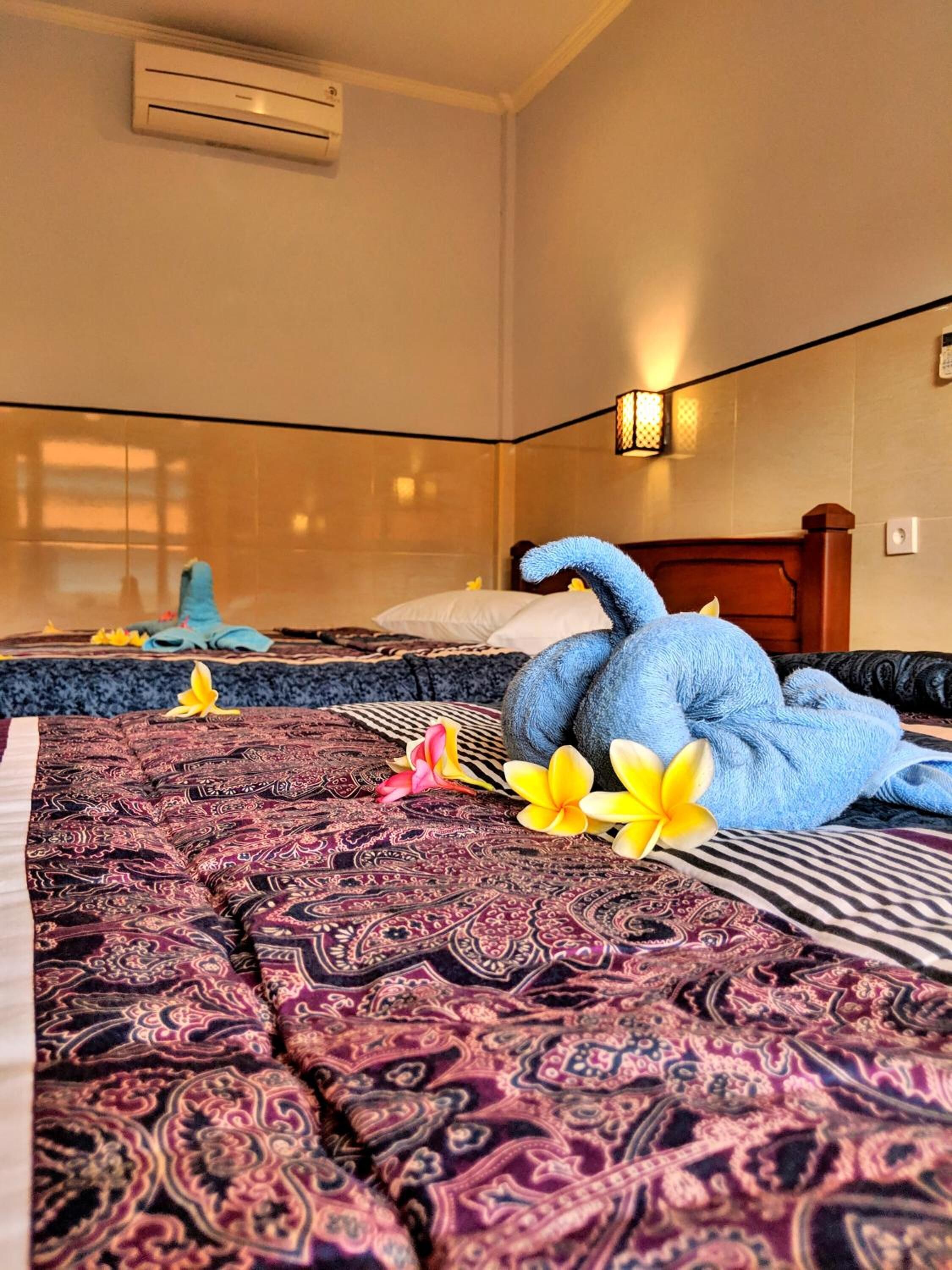 Una habitación de hotel con cama, aire acondicionado de pared y una lámpara decorativa.