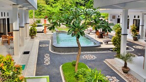 A pool area with a hot tub, surrounded by lounge chairs and a small tree. - Serangan Inn Mimba (Padangbai)