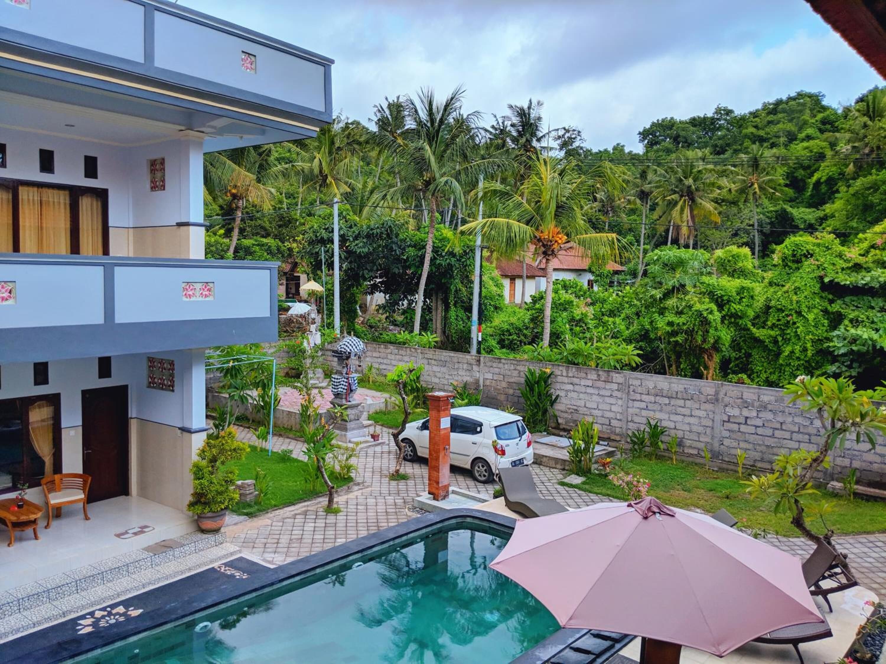 A modern building with a swimming pool, surrounded by lush greenery and palm trees.