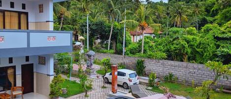 A modern building with a swimming pool, surrounded by lush greenery and palm trees.