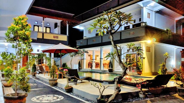 A two-story building with a pool, outdoor seating, and potted plants. - Serangan Inn Mimba (Padangbai)