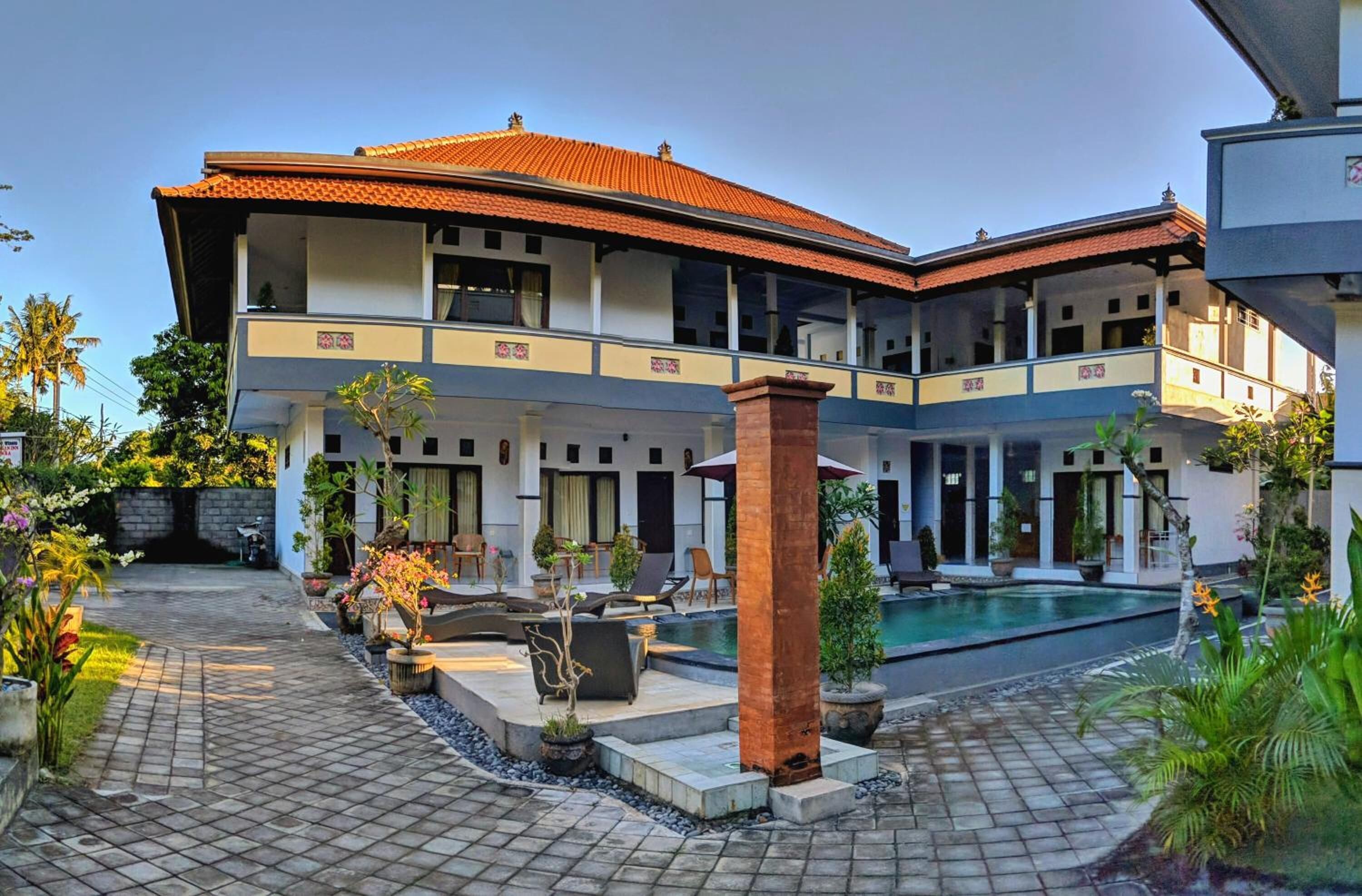 A two-story building with a swimming pool, outdoor seating, and potted plants.