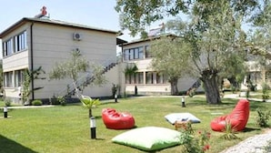 A two-story building with a garden area featuring outdoor seating and a paved walkway.