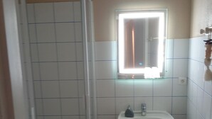 A bathroom with a white sink, a mirror, and a shower. - Ferme Le Grand Cordy (Grignan)