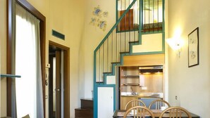 A cozy interior with a staircase leading to a kitchen, a dining area with chairs, and a sofa. - Residence Mirelladue (Ponte di Legno)