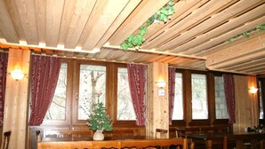 A wooden interior with a piano, a Christmas tree, and a dining table with chairs. - Residence Mirelladue (Ponte di Legno)
