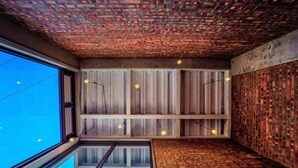 Ein modernes Interieur mit einem Glaspool, Ziegelwänden und Holzleisten.