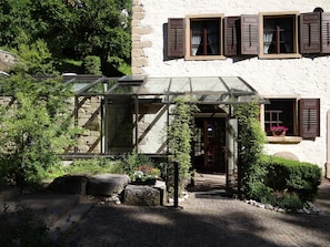 A traditional stone building with a glass conservatory, stone steps, and potted plants. - Bibermühle (Tengen)
