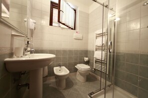 A bathroom with a sink, bidet, toilet, and glass shower enclosure. - Agriturismo Da Giovanni (Peschiera del Garda)