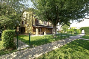 A building with a balcony, surrounded by greenery and a paved pathway. - Agriturismo Da Giovanni (Peschiera del Garda)