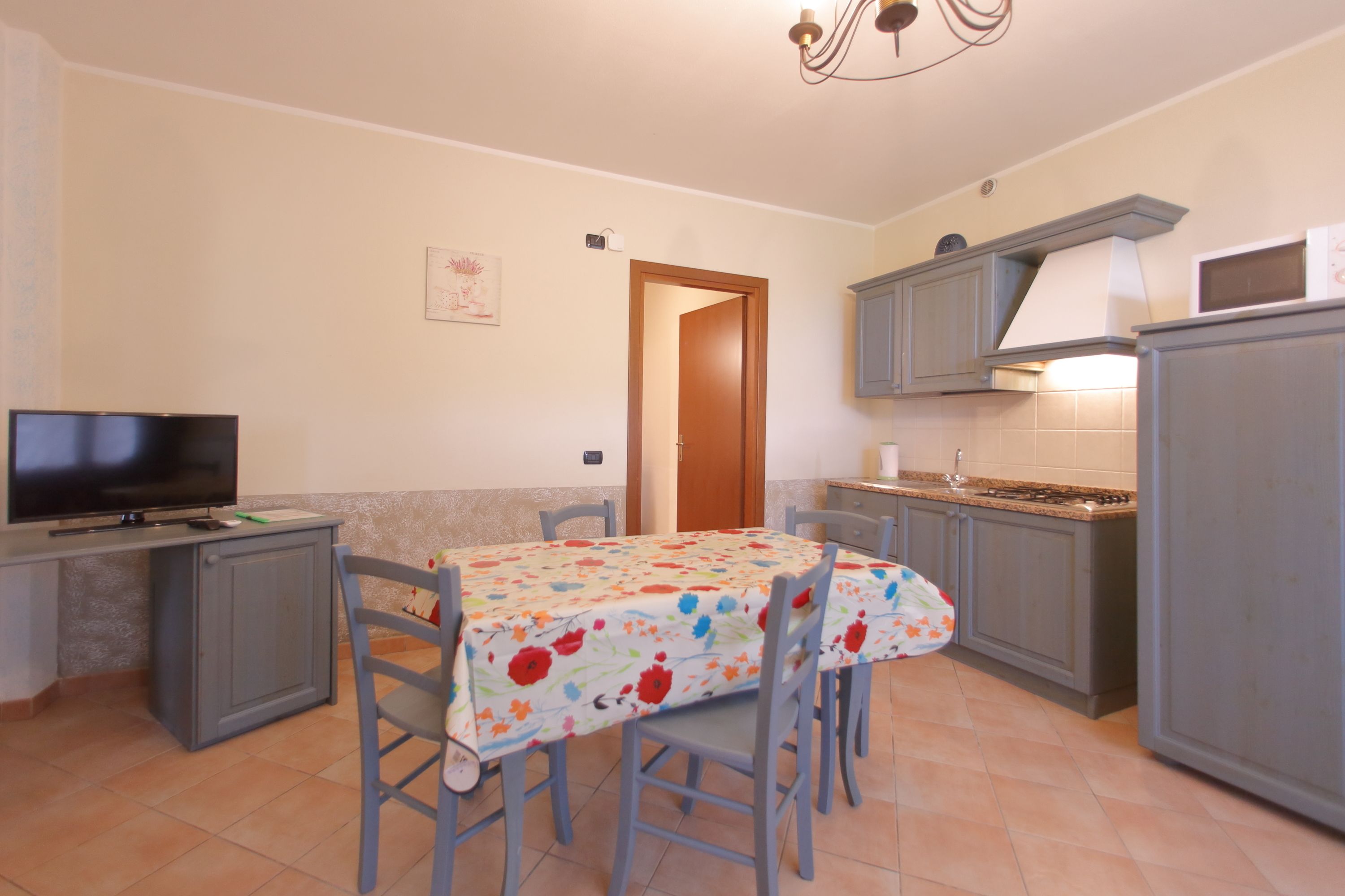 A compact kitchen with a dining table, chairs, a television, and a microwave.