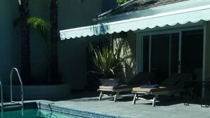 A swimming pool with lounge chairs and a covered area. - Maison Fontainbleau (Cape Town)
