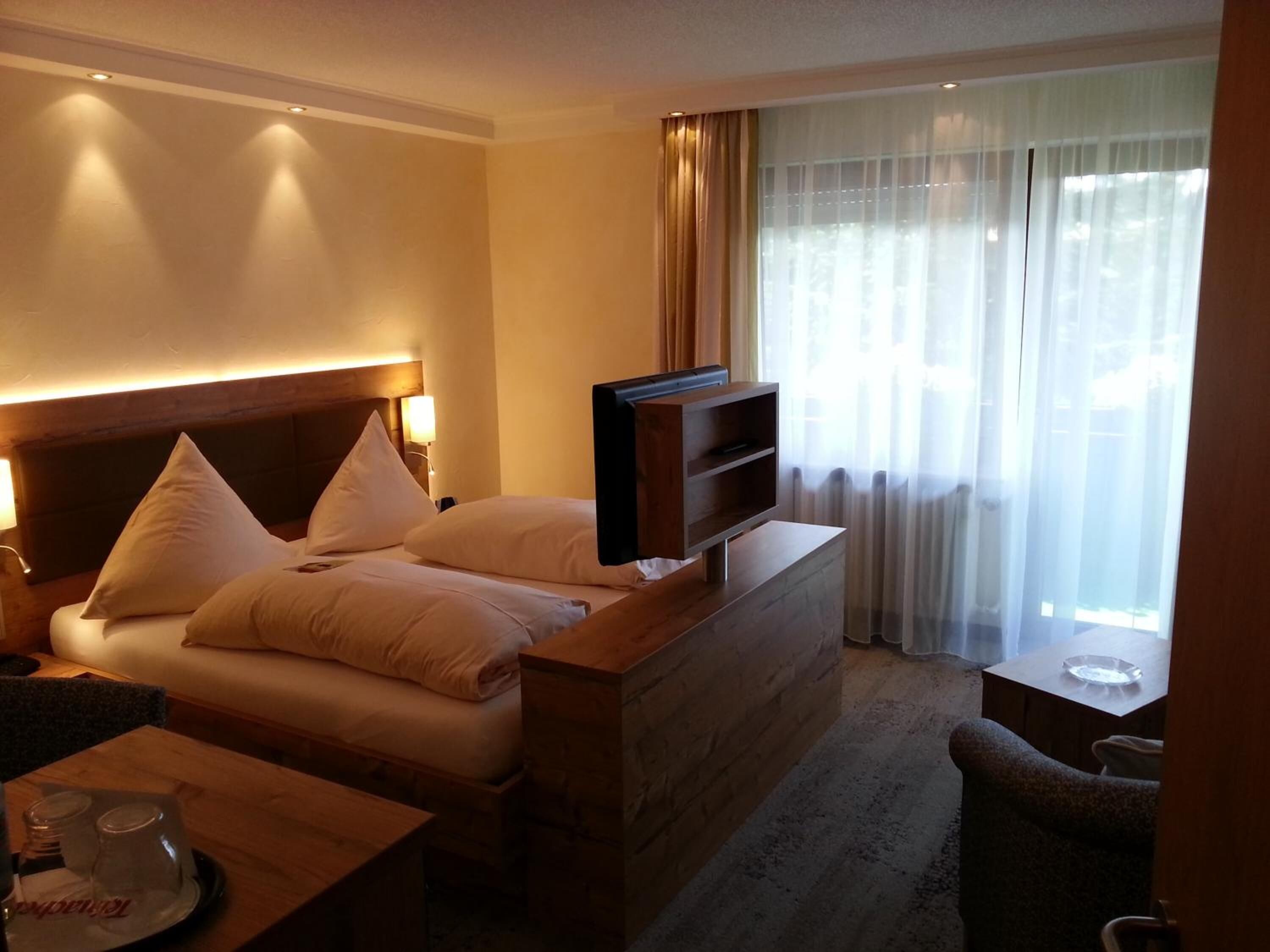 A hotel room with a bed, a TV, a desk, and a chair.