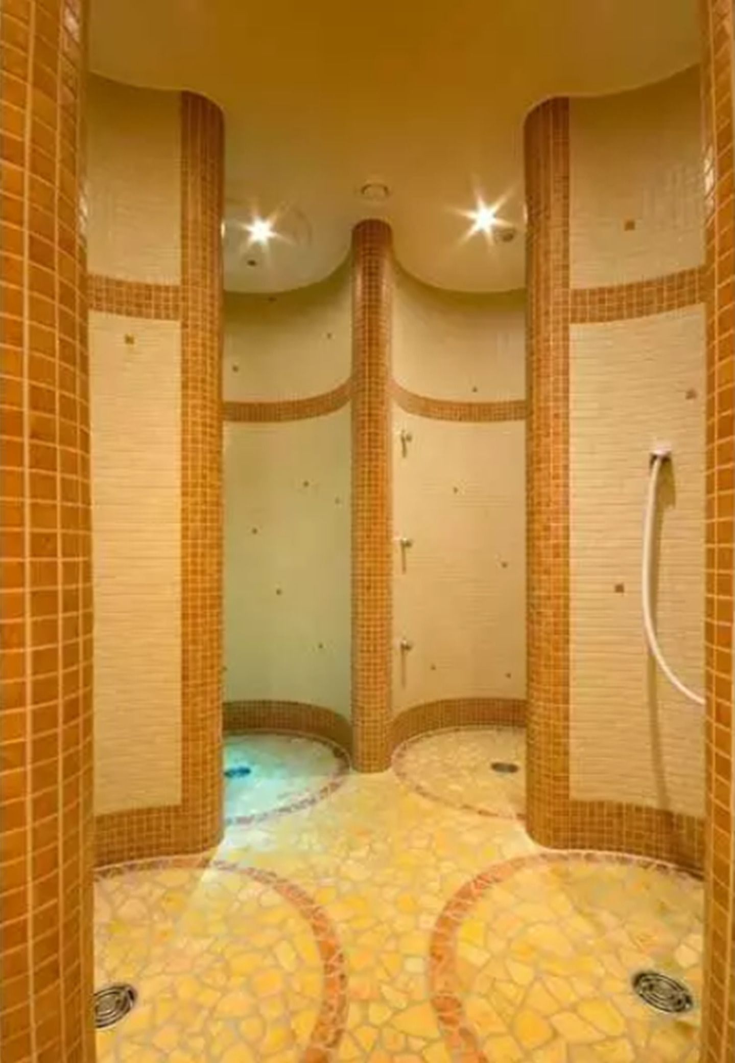 A tiled bathroom with a curved floor design, a shower area, and a visible hand shower.