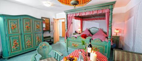 A room with a checkered table set, a bed with a canopy, and a vintage-style chandelier.