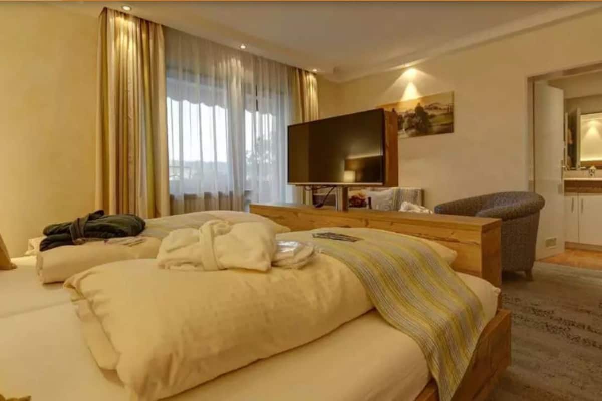 A hotel room with a bed, a TV, a desk, and a chair.