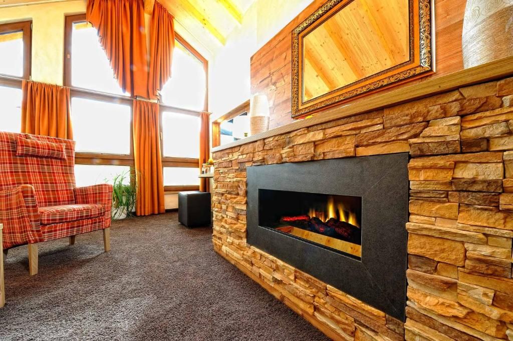 Una habitación acogedora con chimenea, un sofá a cuadros y un ventanal con cortinas.