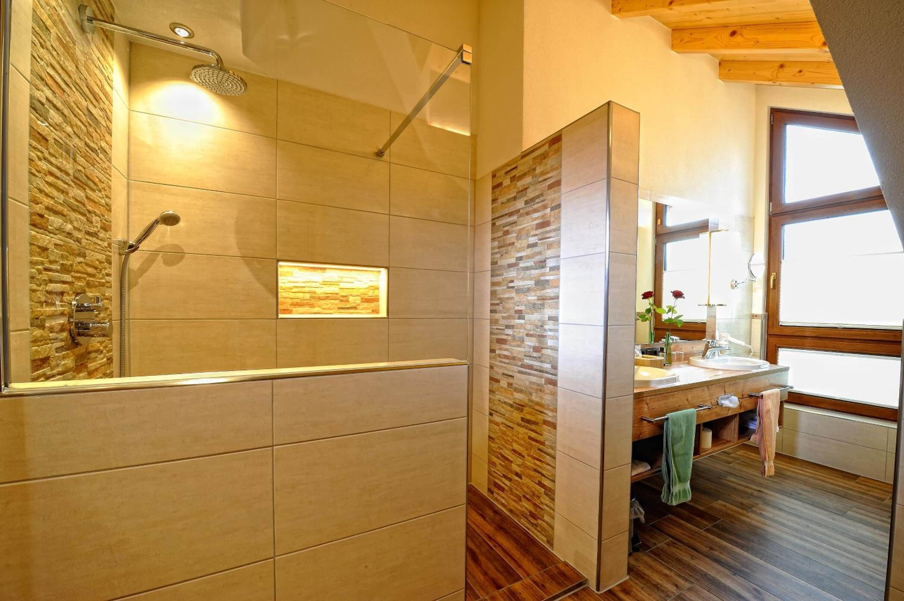 A modern bathroom with a shower, a large mirror, and a wooden vanity.