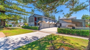 A modern two-story residential building with a covered driveway and a well-maintained lawn. - Adrift Apartments (Yamba)