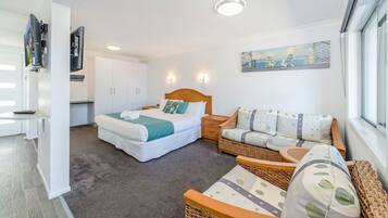 A bedroom with a bed, a sofa, a small table, and a painting on the wall.