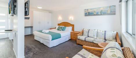 A bedroom with a bed, a sofa, a small table, and a painting on the wall.