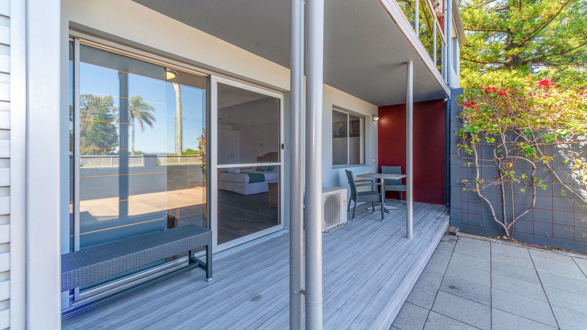 A modern outdoor patio with sliding glass doors, a covered seating area, and a view of the surrounding landscape.