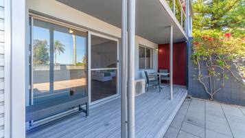 A modern outdoor patio with sliding glass doors, a covered seating area, and a view of the surrounding landscape.