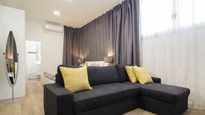 A modern living room with a sectional sofa, two lamps, and a large window with curtains. - Apartment Aspalathos Centar (Split)