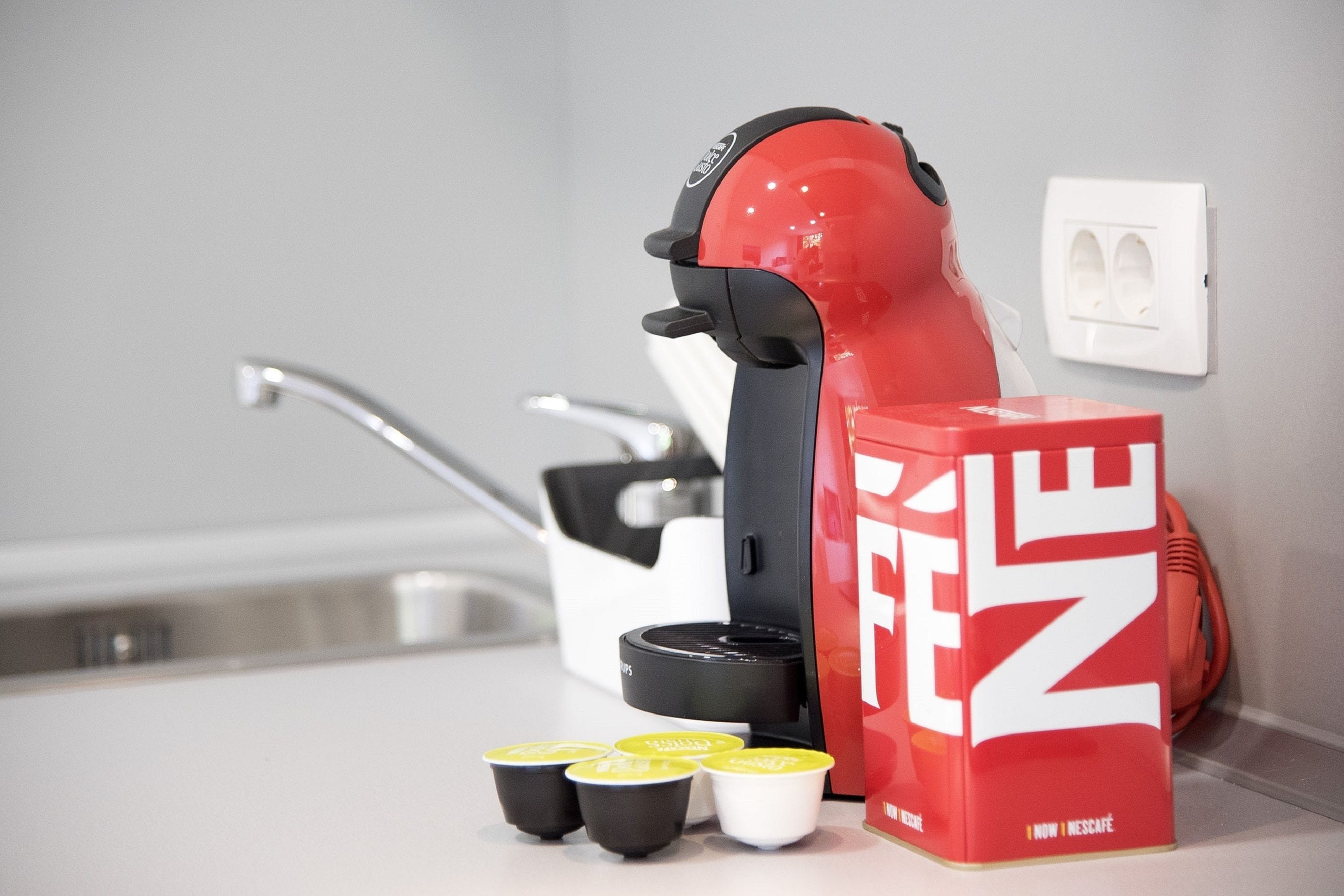 A coffee machine with disposable cups and a red box labeled "Nescafé" on a countertop.