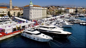 A marina with multiple yachts docked, a large building with a green dome, and a tower in the background. - Apartment Aspalathos Centar (Split)