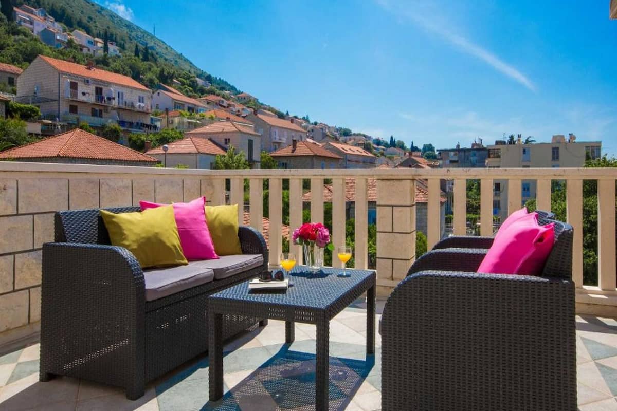 Une terrasse meublée de mobilier en osier, avec une table et une vue sur un village perché sur une colline.