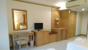 A hotel room with a desk, chair, television, wardrobe, and two beds. - Kresident Hotel (Phitsanulok)