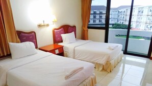 Camera d'albergo con due letti, un comodino, una lampada e vista sugli edifici attraverso un'ampia finestra.