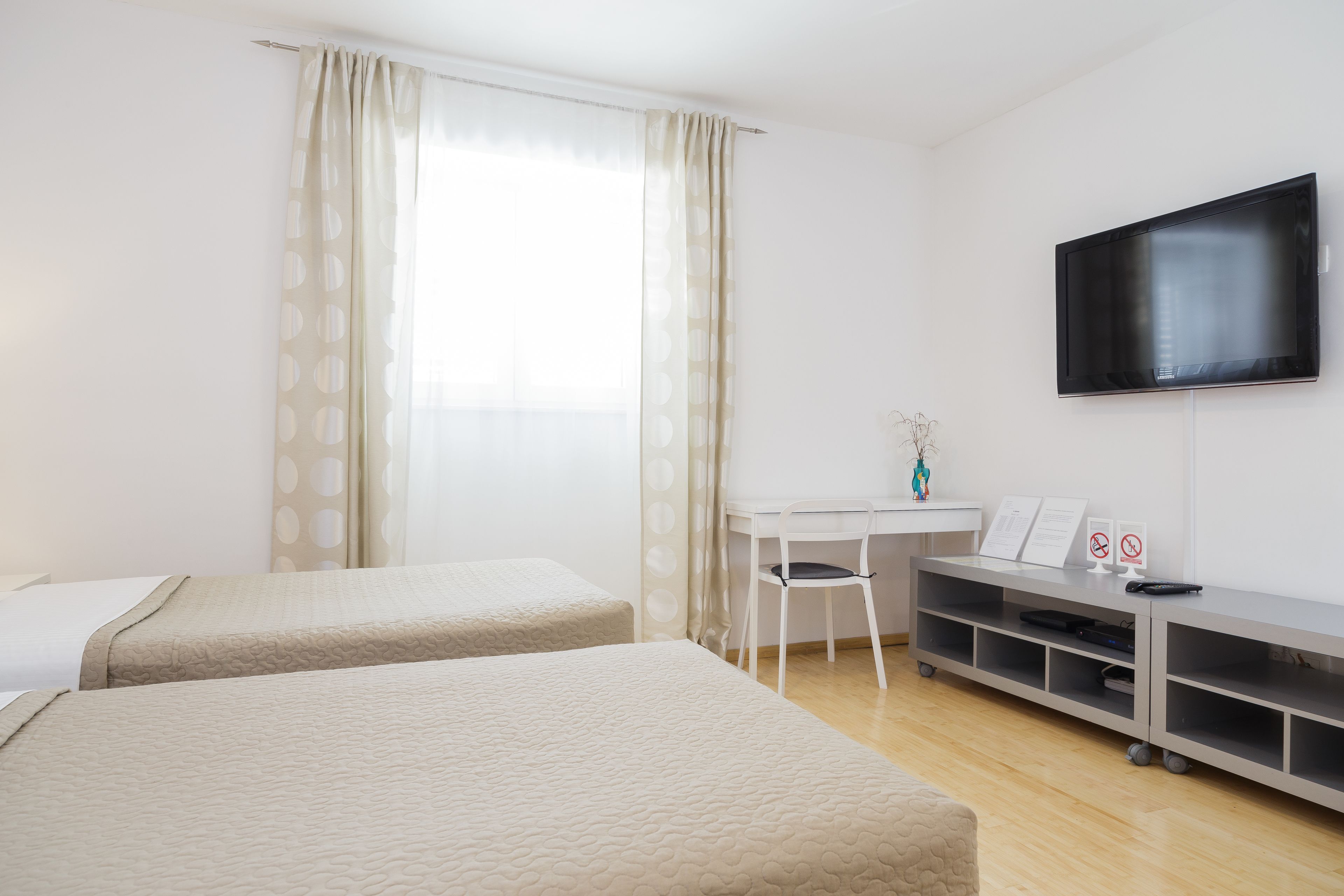Habitación de hotel con dos camas, un escritorio, un televisor y un pequeño rincón de descanso.