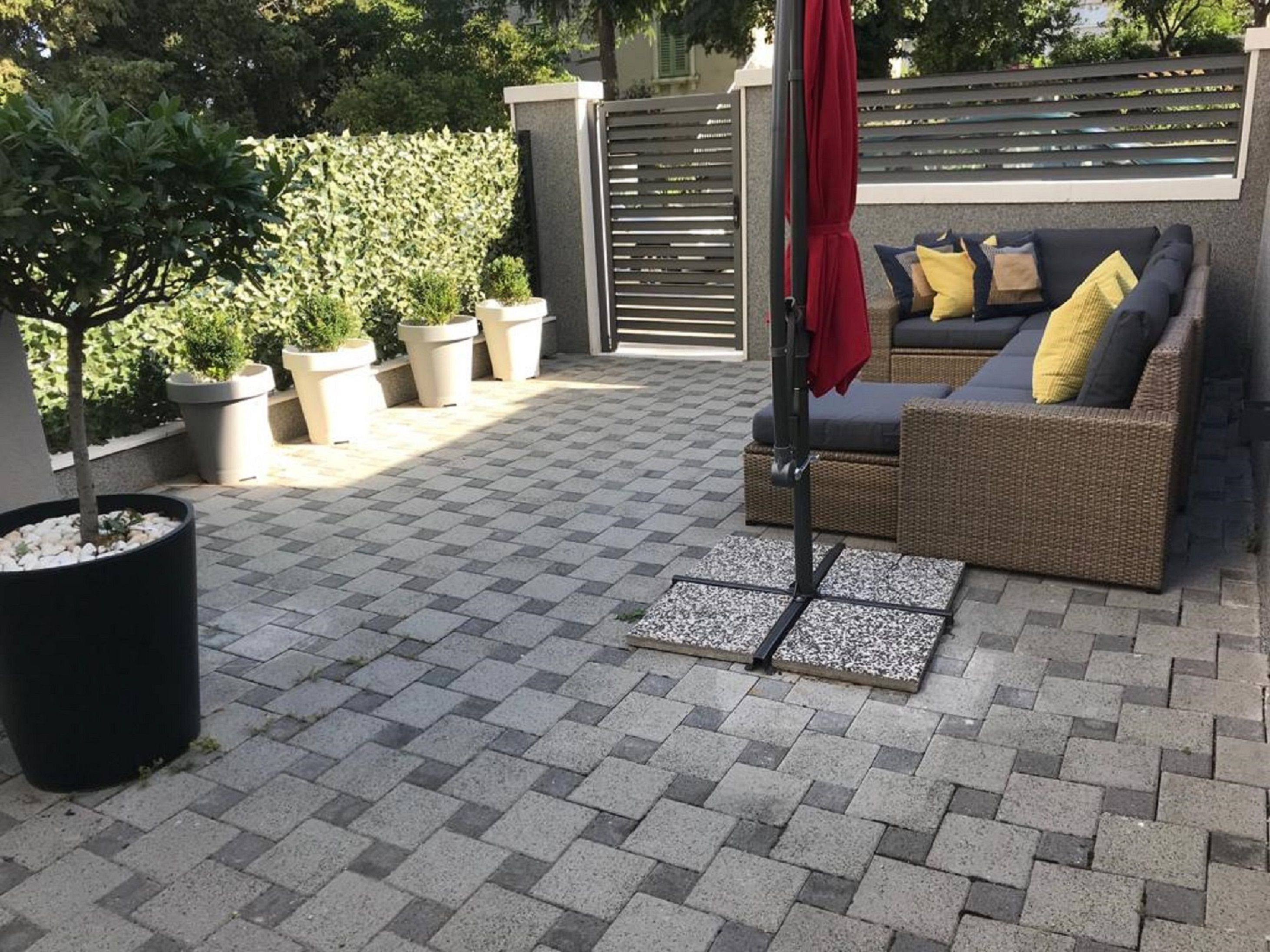 A patio area with a checkered floor, outdoor furniture, potted plants, and a gate.